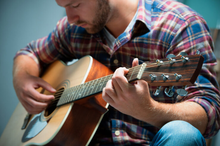 close up of a male musician playing acoustic guitar